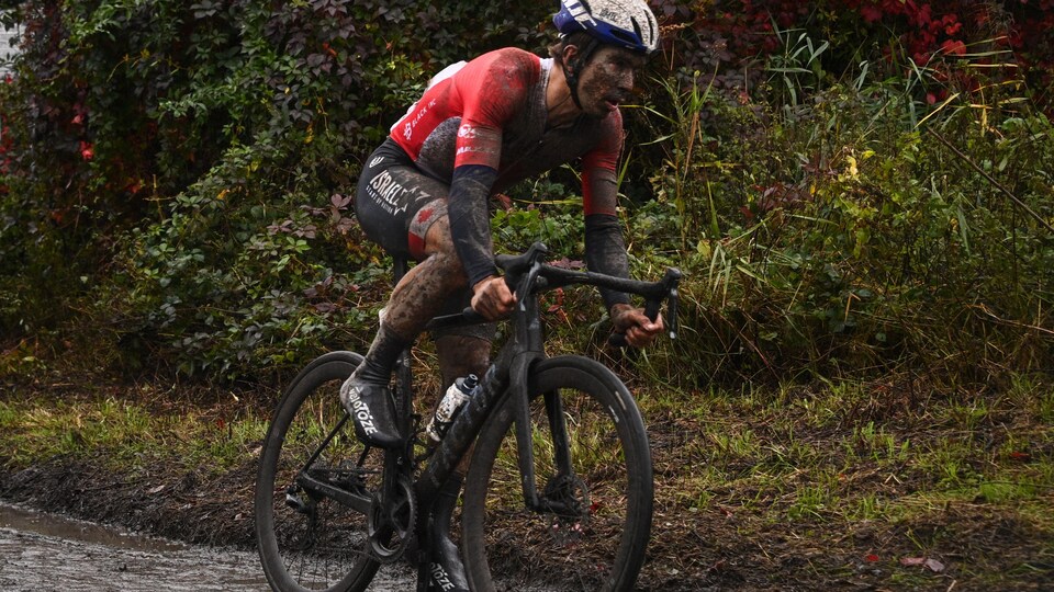 Le cycliste professionnel roule sur sur un chemin boueux.