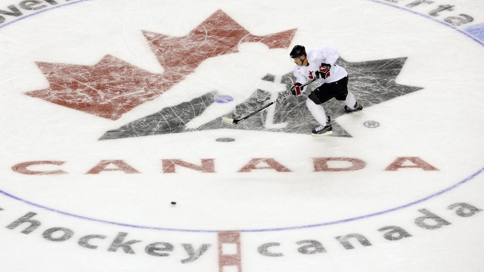 A hockey player skates on ice with the Hockey Canada logo on it