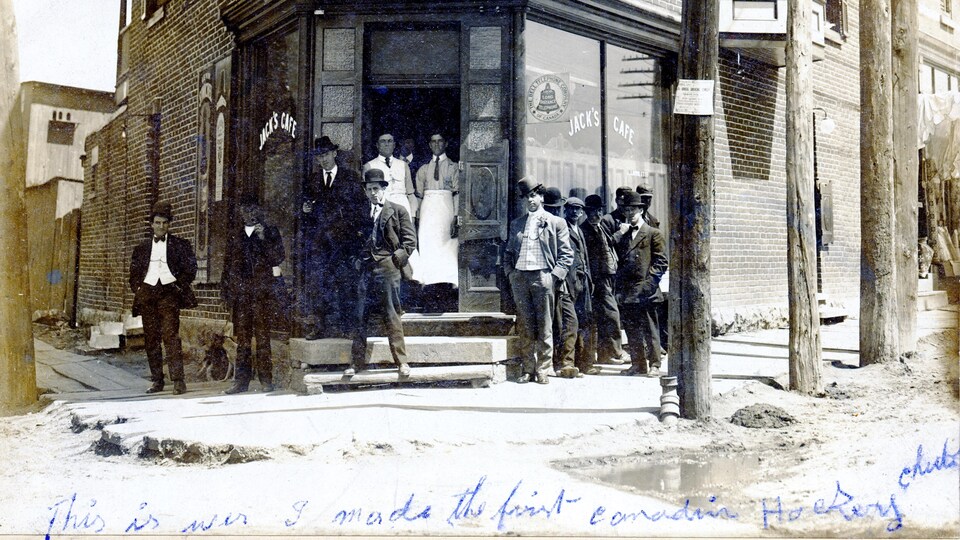 Des hommes prennent la pose devant la façade du commerce.