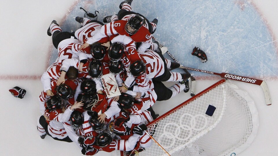 Des joueuses de hockey célèbrent près du filet