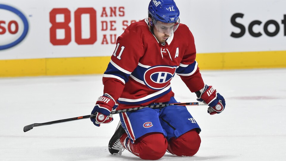 Il est agenouillé sur la glace.