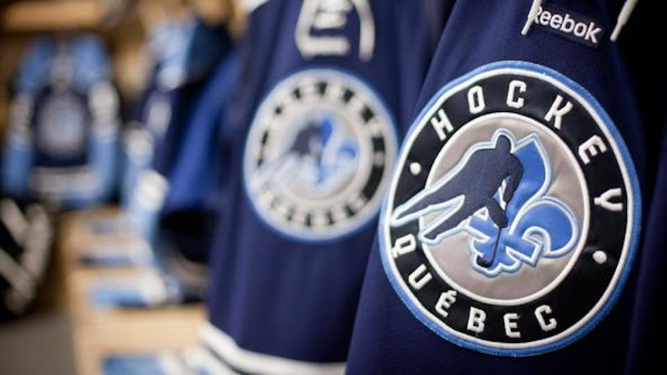 Des chandails de hockey bleus, sur lesquels on retrouve de le logo de Hockey Québec