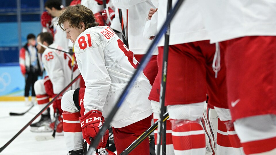 Des joueurs de hockey alignés sur la glace, certains ont un genou au sol.