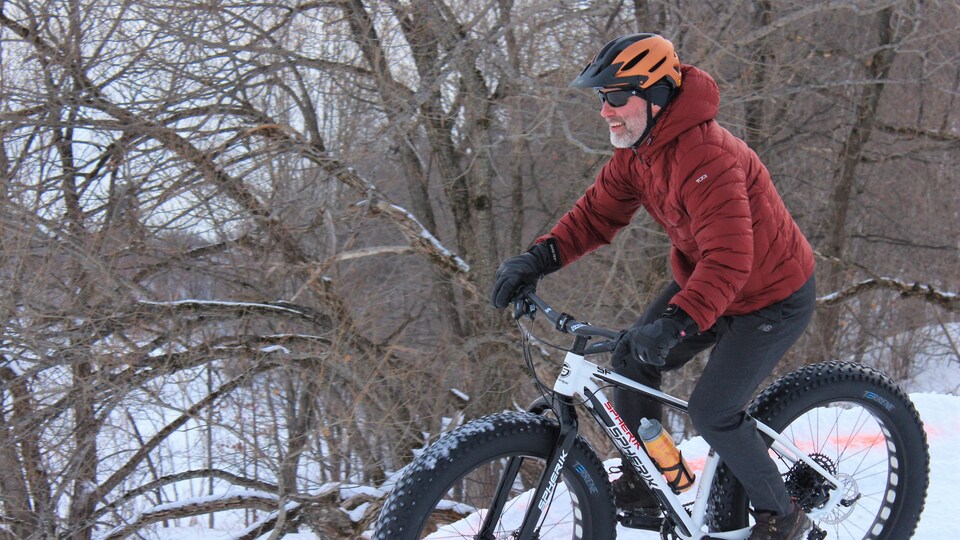 Un homme fait du vélo l'hiver