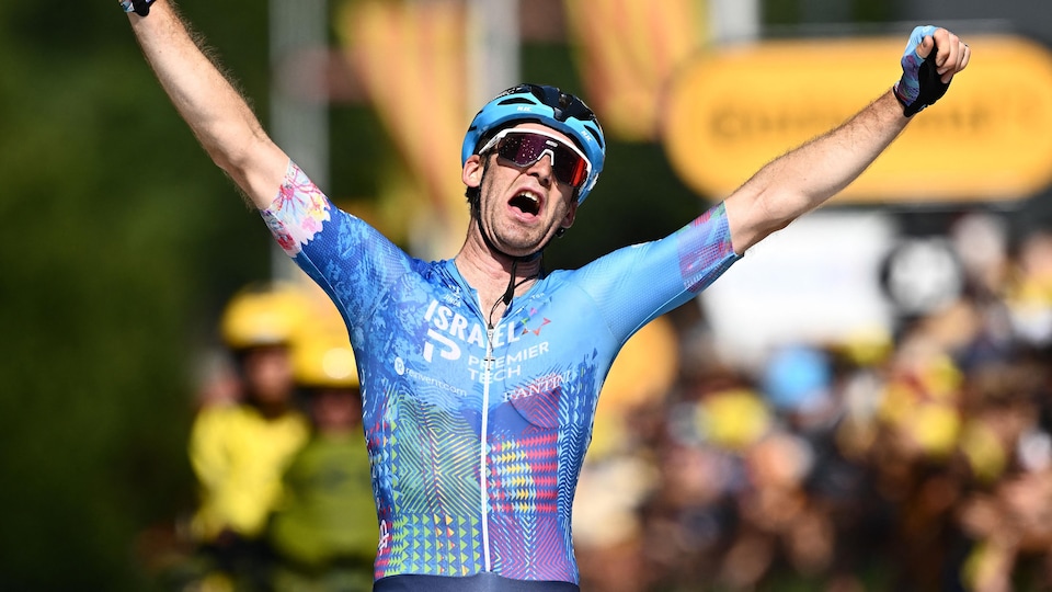 Le cycliste Hugo Houle lève les bras vers le ciel après sa victoire.