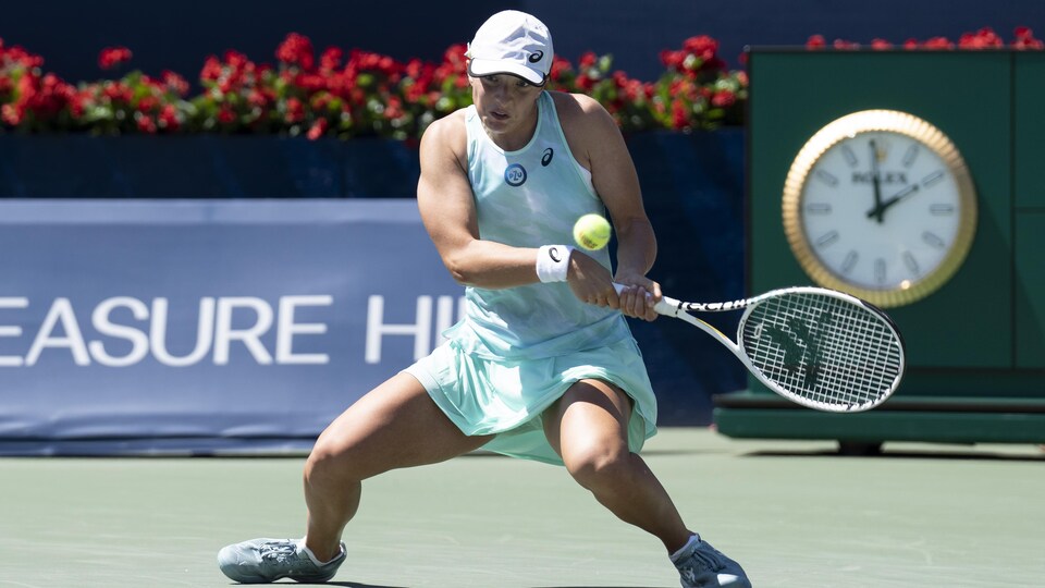 A tennis player is about to hit a ball with her racket.