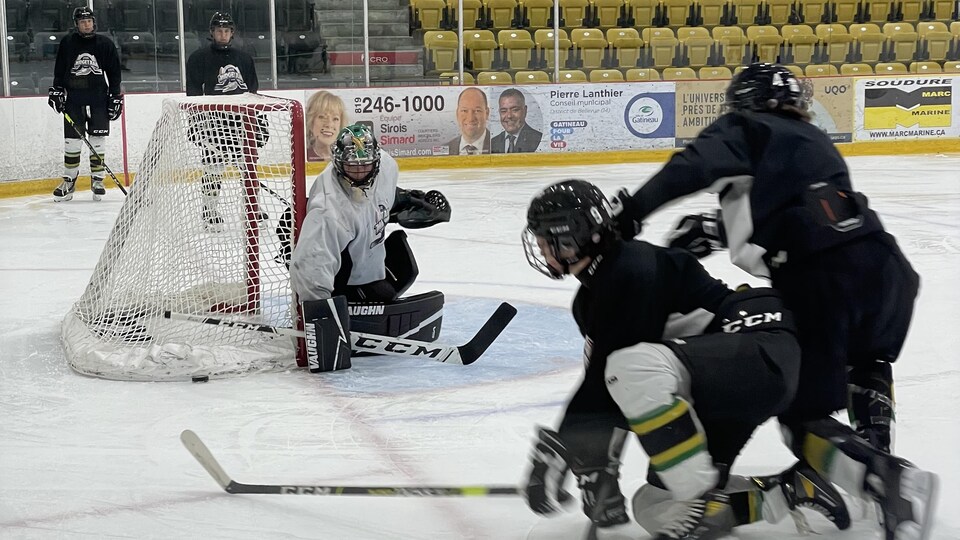 Des joueurs de hockey se disputent la rondelle devant leur gardien pendant un entraînement.