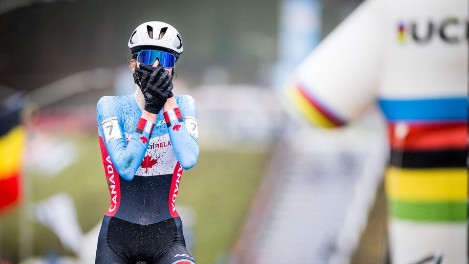 Une cycliste porte ses mains à son visage alors qu'elle passe la ligne d'arrivée la première.