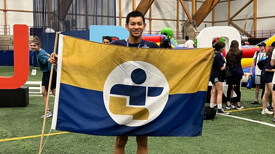 Isidore Warain tient un drapeau de l'Outaouais dans ses mains.