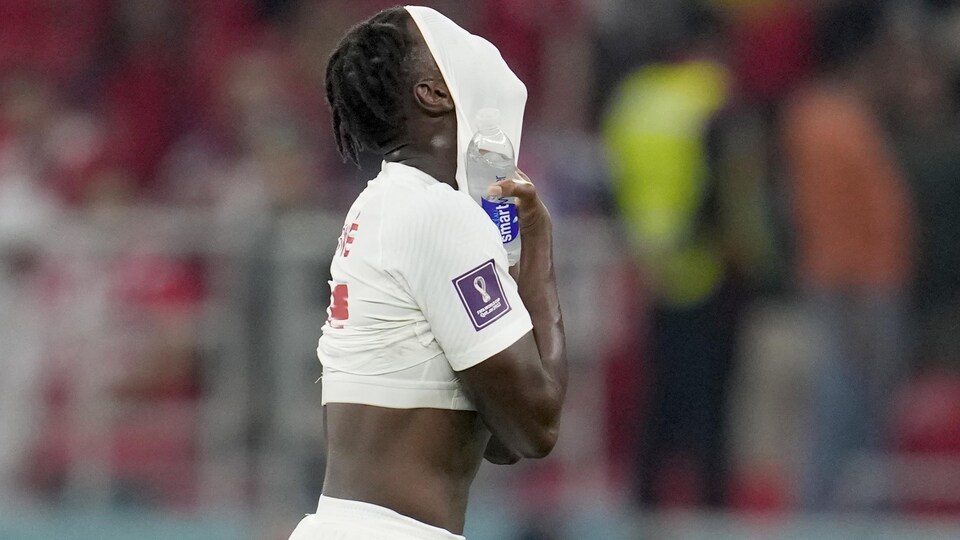 Un footballeur couvre son visage avec son maillot. 