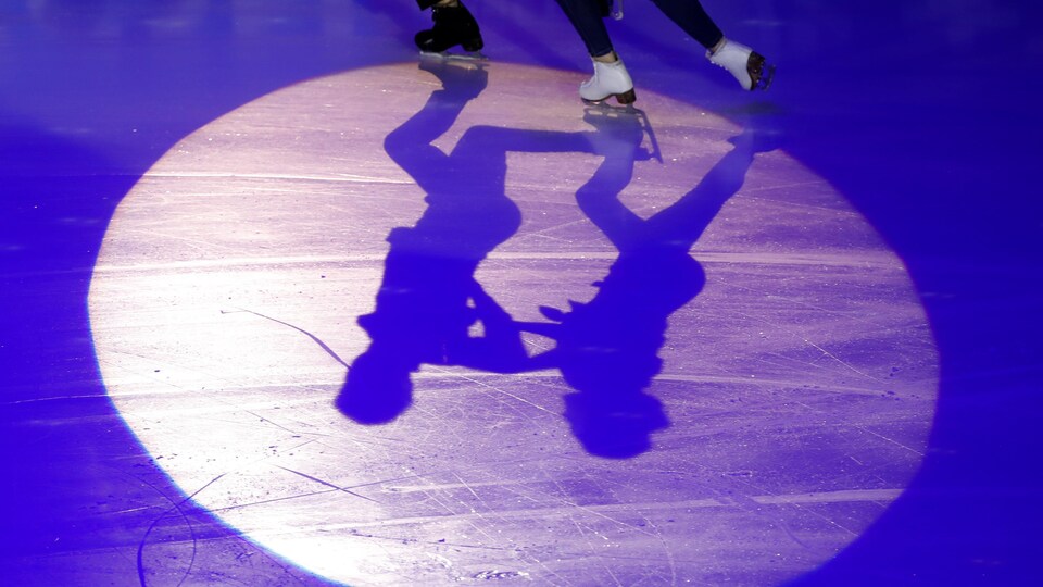 Les ombres de patineurs artistiques durant une compétition.