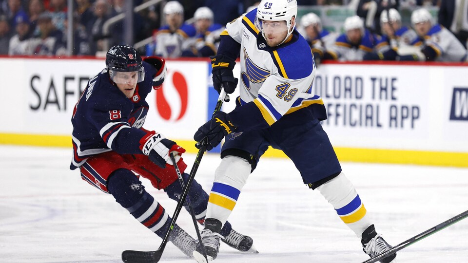 Le joueur des Jets tente d'enlever la rondelle à Barbashev, des Blues.
