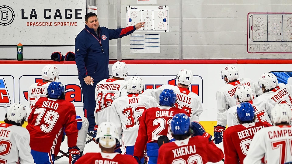 Il donne ses instructions aux joueurs agenouillés sur la glace.