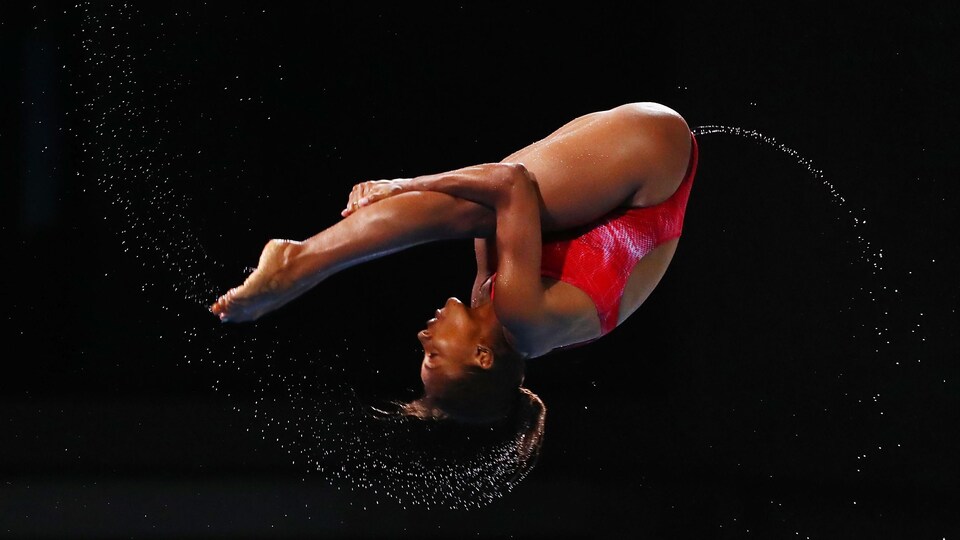 Elle est en position carpée dans les airs.