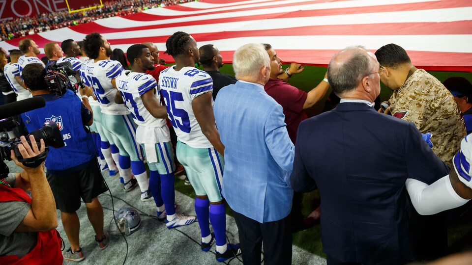Sep 25, 2017; Glendale, AZ, USA; Dallas Cowboys owner Jerry Jones (blue) locks arms with his players on the sidelines during the national anthem prior to the game against the Arizona Cardinals at University of Phoenix Stadium. Mandatory Credit: Mark J. Rebilas-USA TODAY Sports - 10308262
