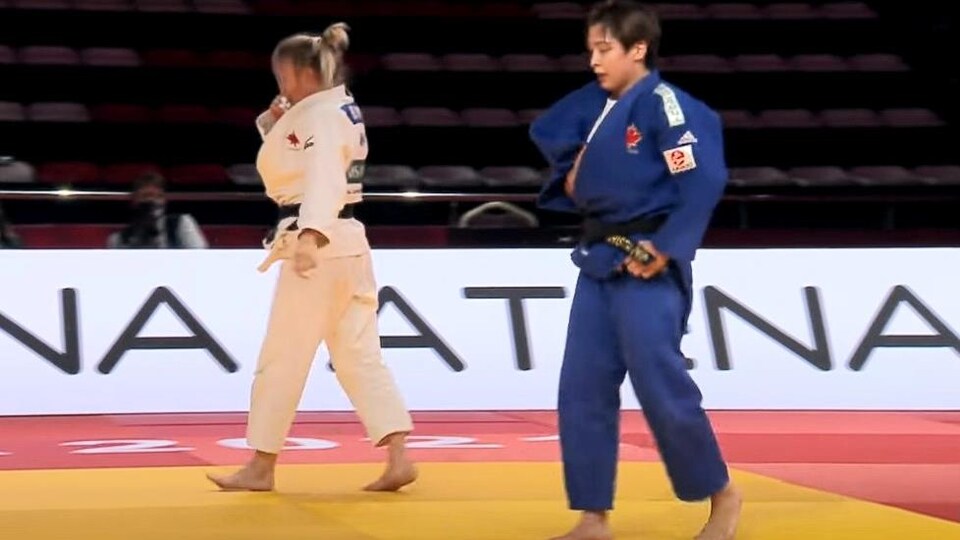 Christa Deguchi, en judogi azul, y Jessica Klimkait caminan sobre el tatami durante una pelea.