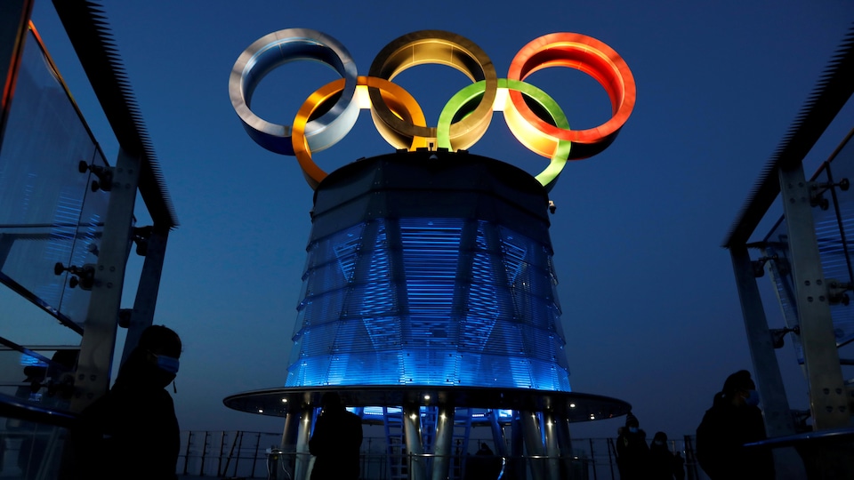 Les anneaux olympiques sont illuminés au sommet d'une structure.