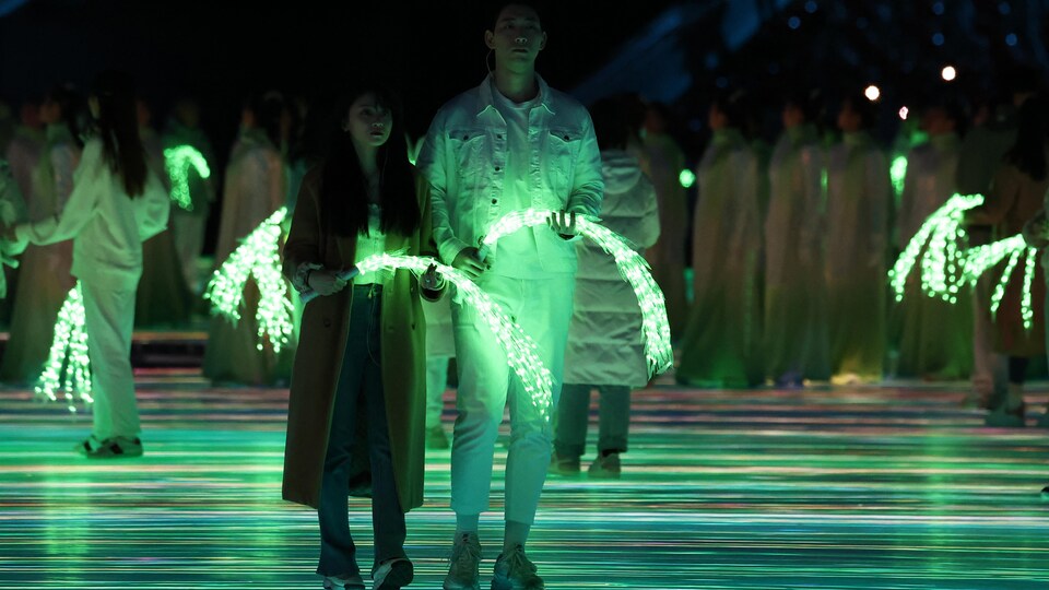 Des Chinois tiennent dans leurs mains des branches de saule illuminées en vert.
