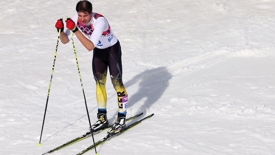 Un skieur en manches courtes met son poids sur ses bâtons. 