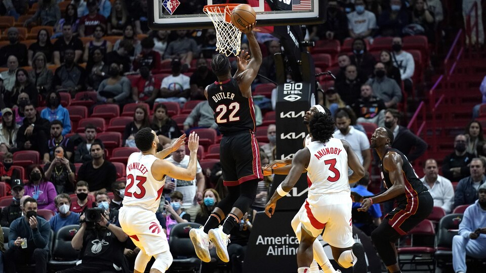 Un joueur de basketball saute près du panier avec le ballon.