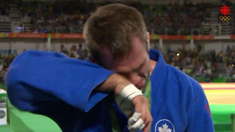 Un judoka essuie ses larmes sur sa manche droite pendant une entrevue.