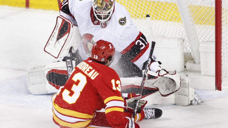 Un joueur de hockey assis sur la glace et un gardien de but.