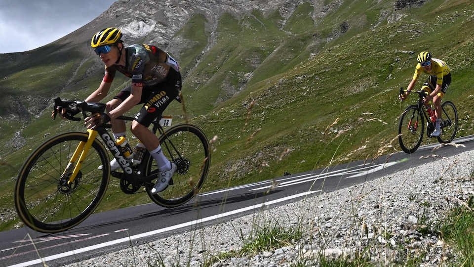 Un cycliste roule devant le maillot jaune en montagne.
