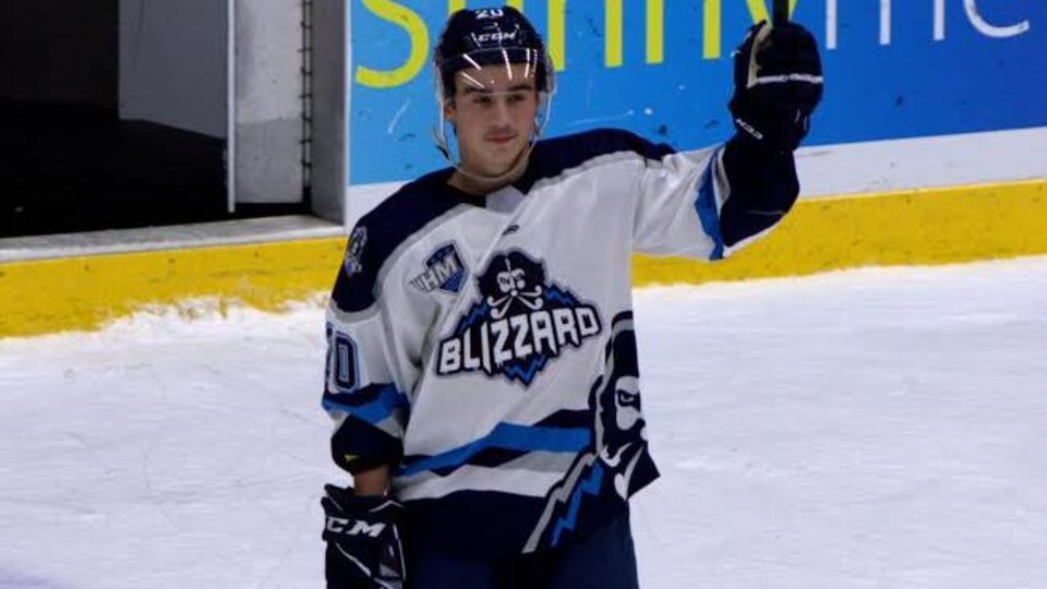 Joueur de hockey levant son bâton en signe de reconnaissance.