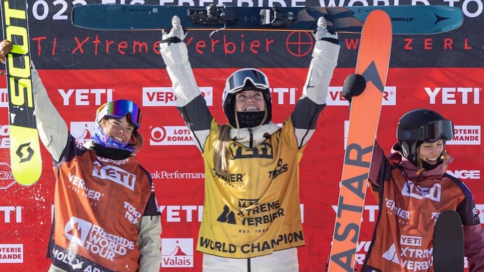 Trois skieuses lèvent les bras sur le podium. 