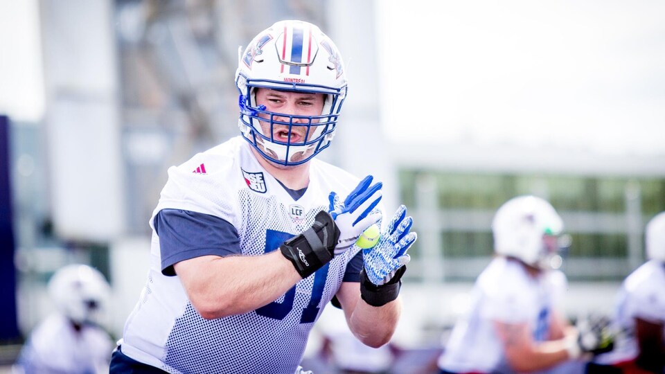 Un joueur de football lève ses mains pour effectuer un exercice de bloc à l'entraînement.