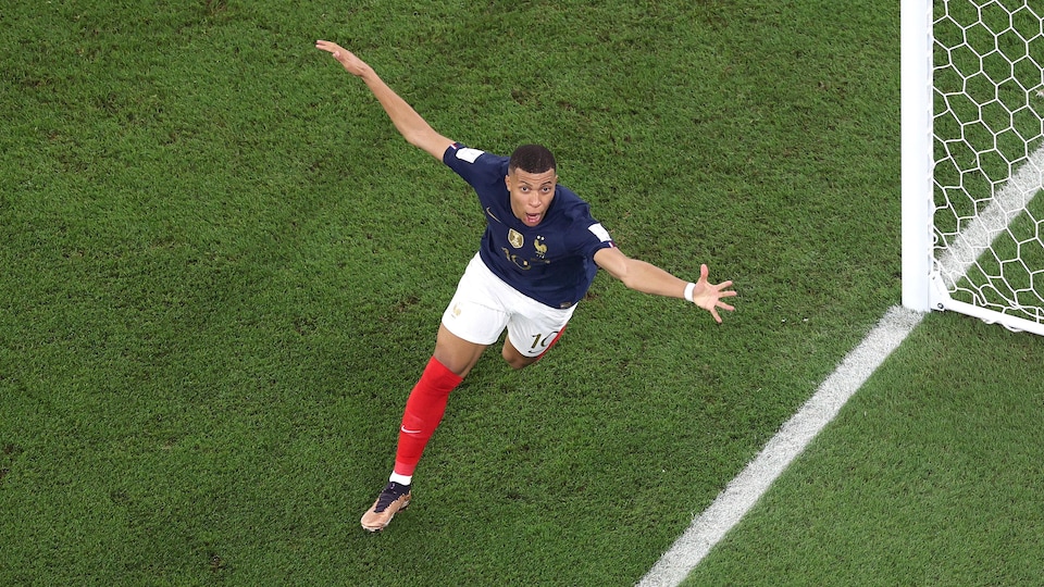 Un joueur de soccer célèbre un but en ouvrant les bras.