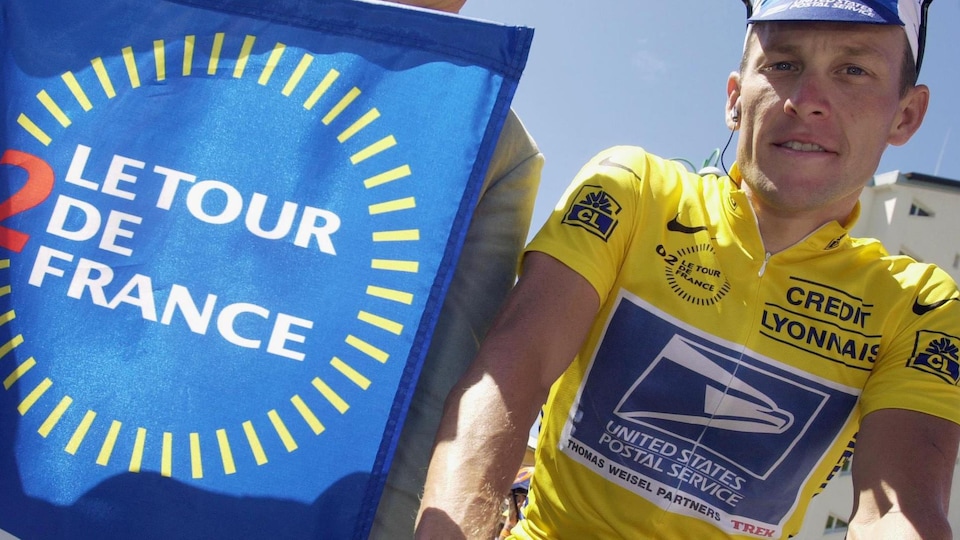 A cyclist in yellow near the Tour de France poster