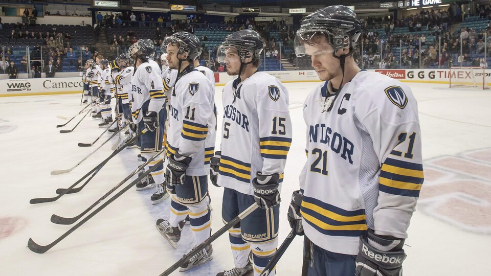 Plusieurs coéquipiers d'une équipe de hockey prennent place sur la ligne bleue.