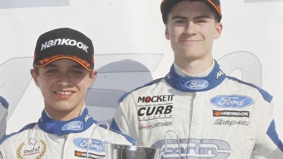 Deux jeunes pilotes souriants avec leurs trophées sur un podium