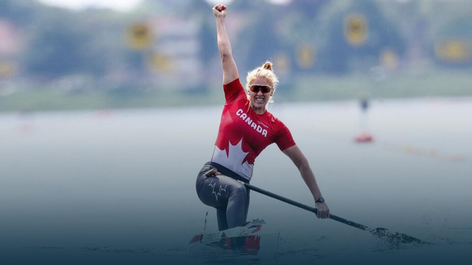 Elle lève un poing en signe de victoire après une course de canoë.