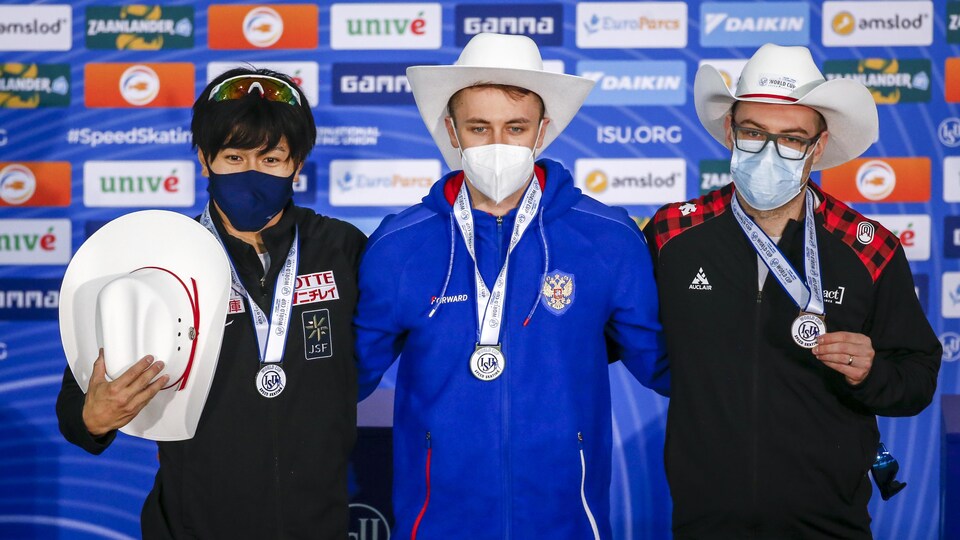 Trois hommes avec des chapeaux montrent leur médaille.