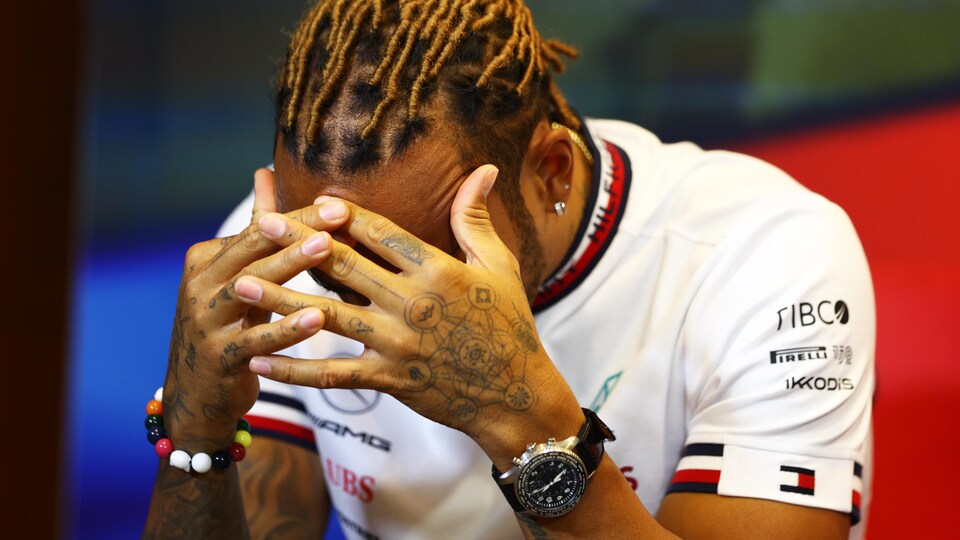 Un pilote de course automobile prend son visage entre ses mains. 