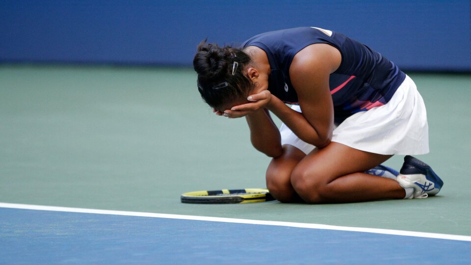 La joueuse de tennis, accroupie au sol, cache son visage avec ses mains.