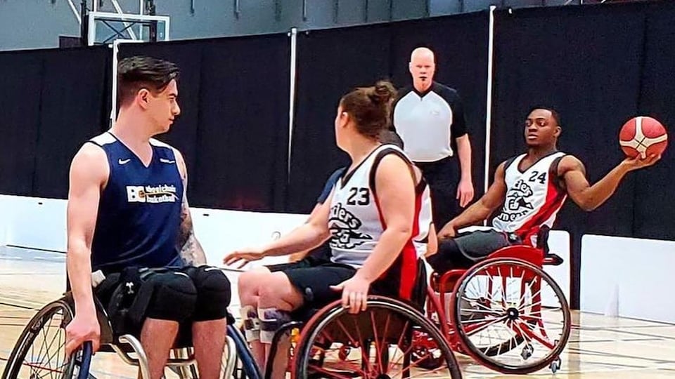 Three wheelchair basketball players on a court.