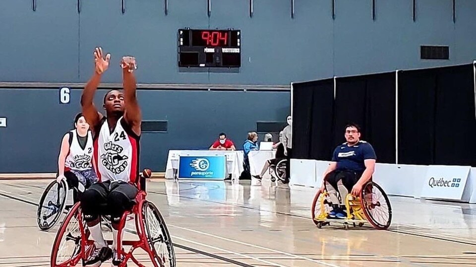 A basketball player in a wheelchair throws a ball into the basket.