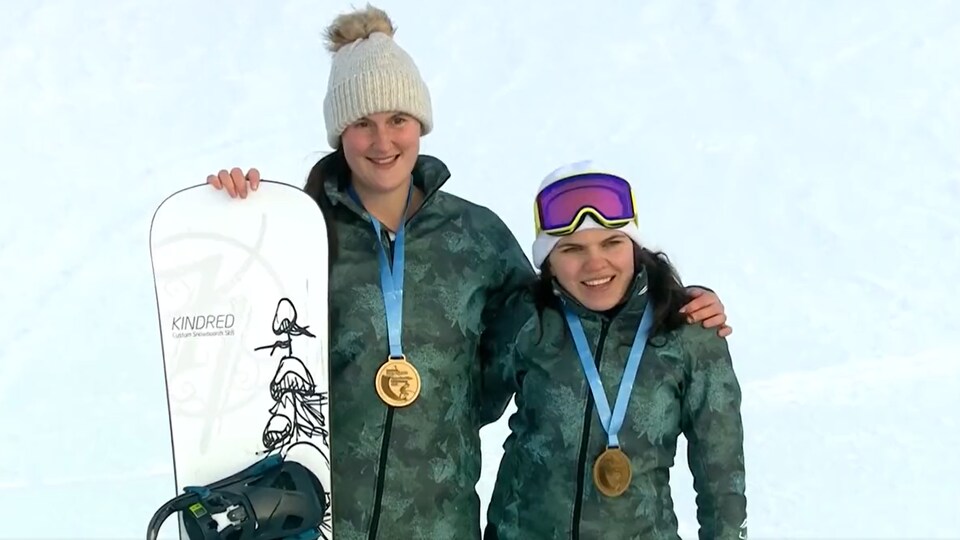 Les deux athlètes de parasurf posent avec leur médaille d'or et une planche à neige. 