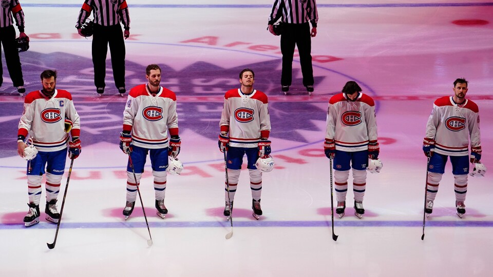 Des joueurs du Canadien se tiennent debout pendant l'hymne national devant le logo des Maple Leafs.