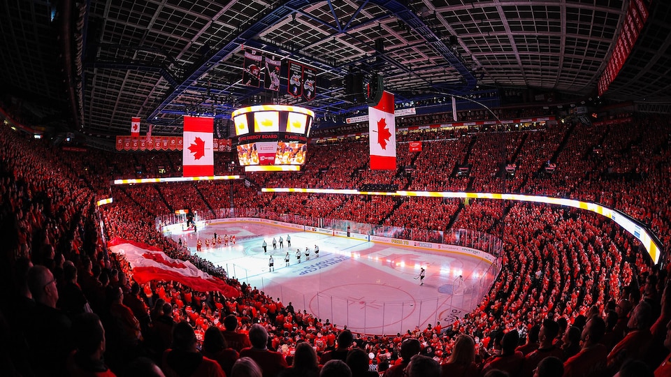Photo du domicile des Flames de Calgary bondé de spectateurs, avec un drapeau canadien à l'écran géant.