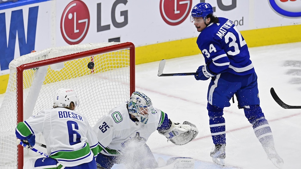 La rondelle passe par-dessus l'épaule du gardien des Canucks.