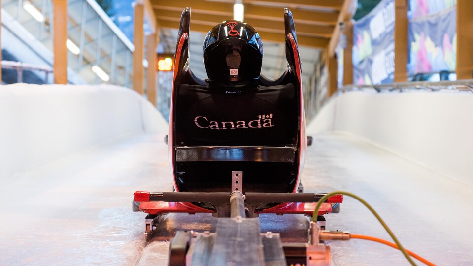 Un piston mécanique est situé derrière un bobsleigh, dans lequel se trouve Lonnie au sommet d'une descente glacée. 