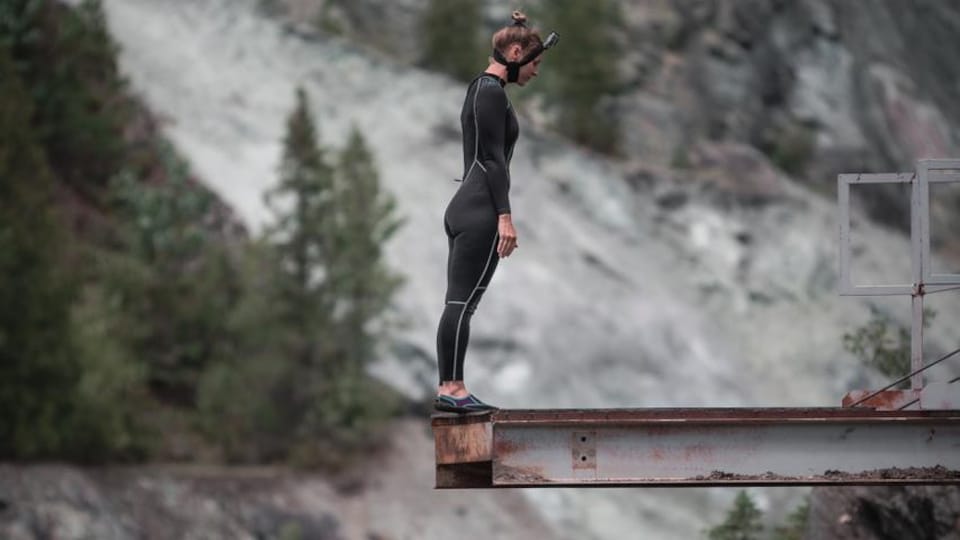 Elle se tient debout au bord d'une plateforme, prête à plonger.