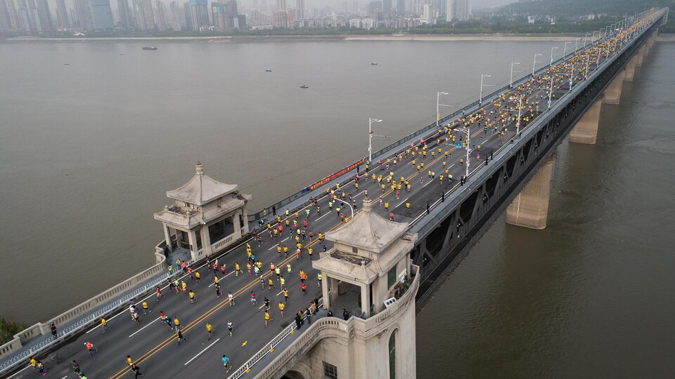 Des marathoniens courent sur un pont.