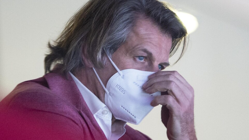 Le directeur général du Canadien, masqué, observe l'action sur la glace.