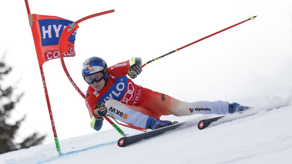 Le skieur suisse Marco Odermatt négocie un virage, sa hanche droite tout près de la neige. 