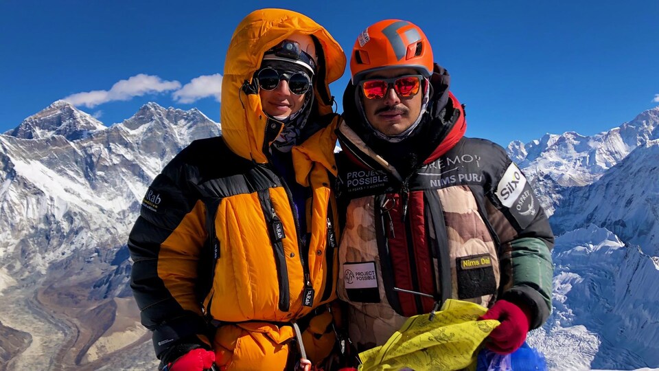 Dos escaladores posan en la cima de una montaña en Nepal. 